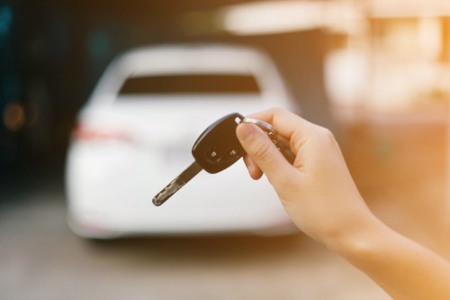 Female holding car keys with car on background